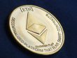 Ethereum symbol debossed on a gold coin on top of a navy blue fabric