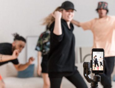 people recording themselves dancing while in front of a smartphone at their living room