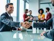 Close-up handshake between agency leader and client at a conference table, with a diverse marketing team collaborating in a bright, modern open-plan office in the background; no visible text, charts, or screens.